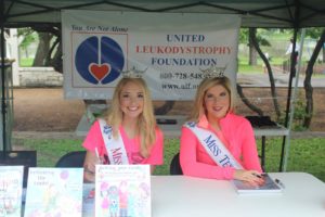 Two beauty queens wearing pink tops and smiling